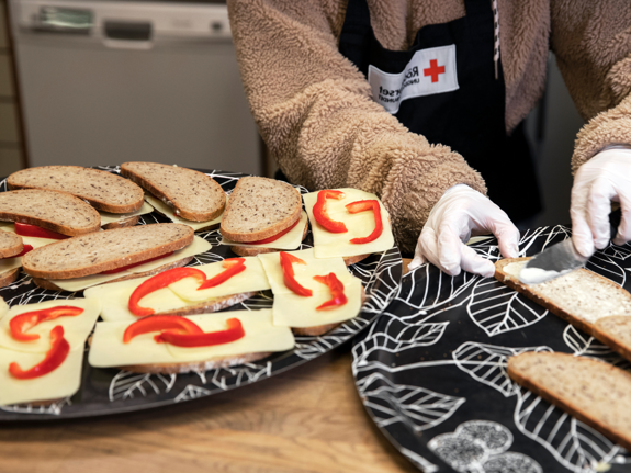 Person gör mackor till Röda Korsets Ungdomsförbunds frukostklubb.